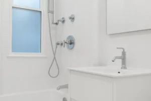 Compact white bathroom with sleek chrome fixtures, handheld showerhead, and modern vanity designed for cost-effective shower upgrades
